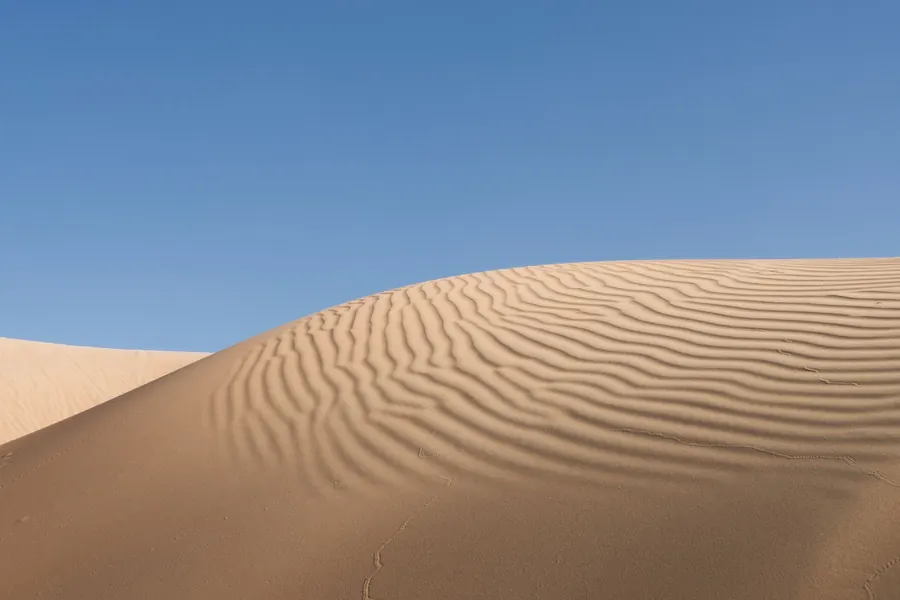Dune di sabbia nel deserto dell'Oman sotto il cielo azzurro
